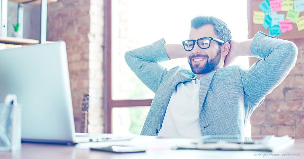 bearded man with glasses sitting back at desk